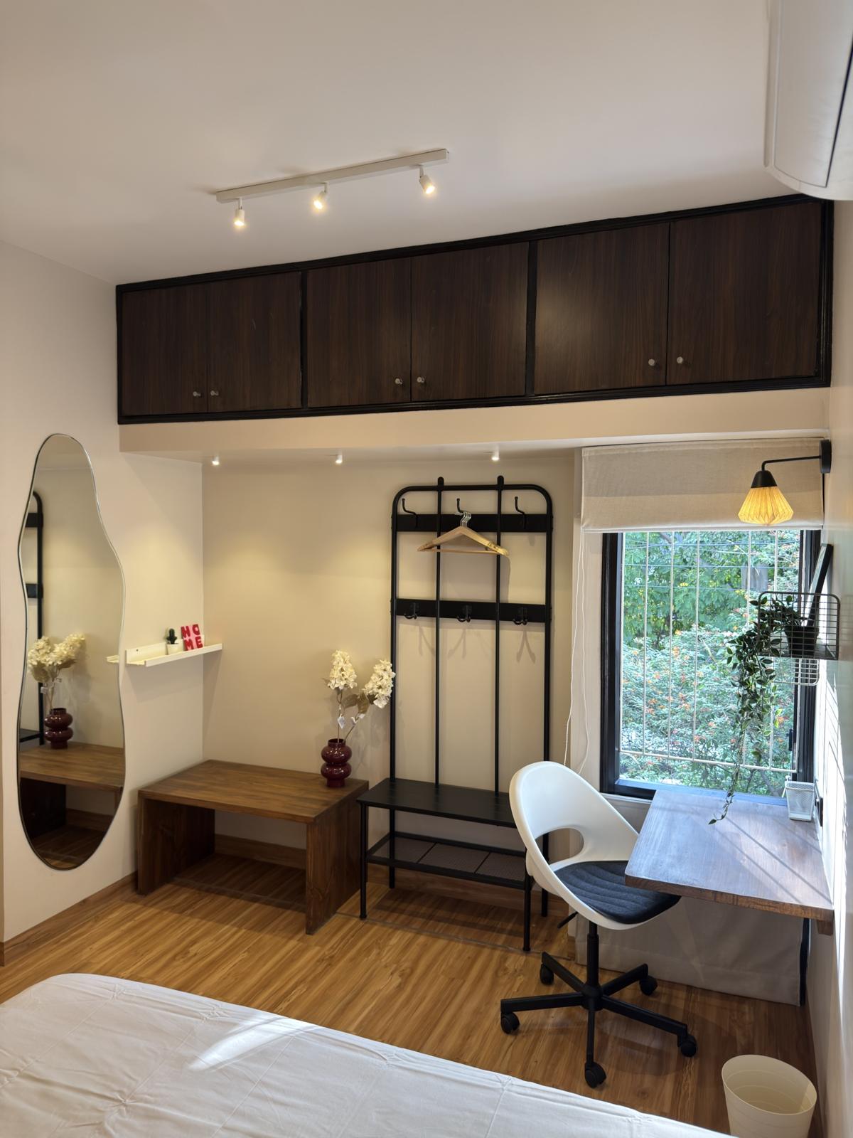 Bedroom with a wavy mirror, coat rack and a desk by the window